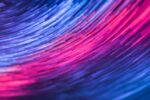 This image shows streaks of pink, purple and blue light in arcs across a black background