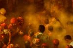 A group of men in colourful clothing throwing coloured powders.